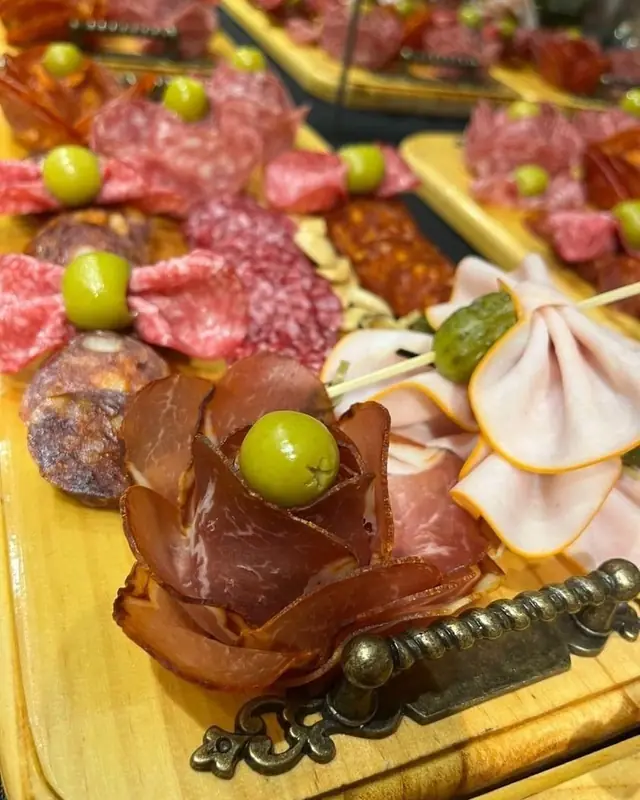 Detalle de una tabla de fiambres con aceitunas y rosas de jamón