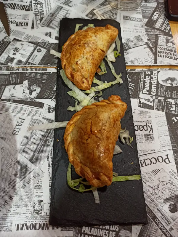 Dos empanadas criollas al horno sobre una pizarra