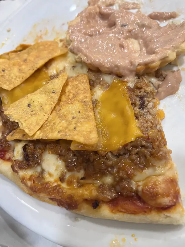 Porción de pizza con carne y nachos, al estilo de la Gringa