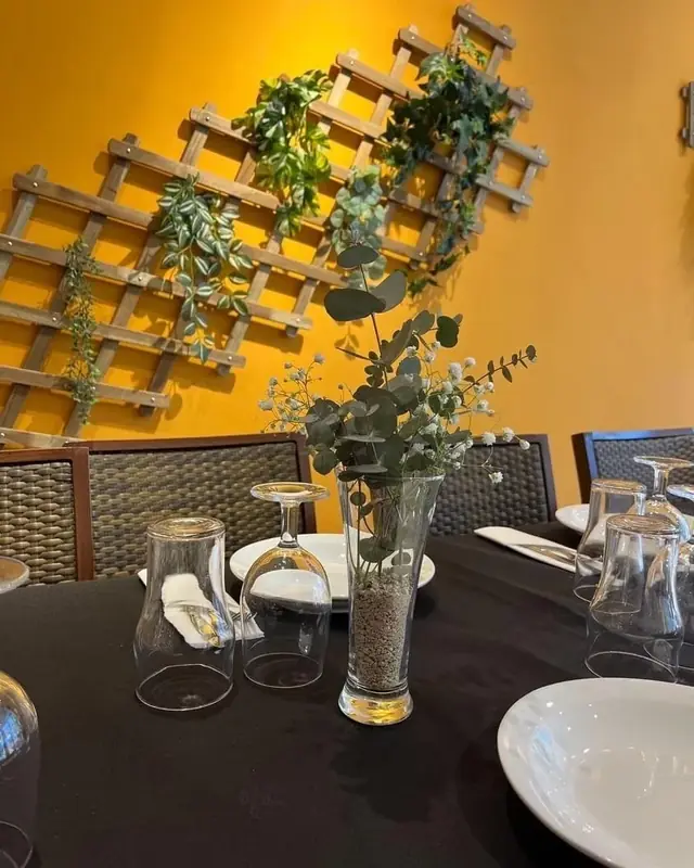 Mesa preparada en el salón de eventos de Tía Tota, con eucalipto y copas